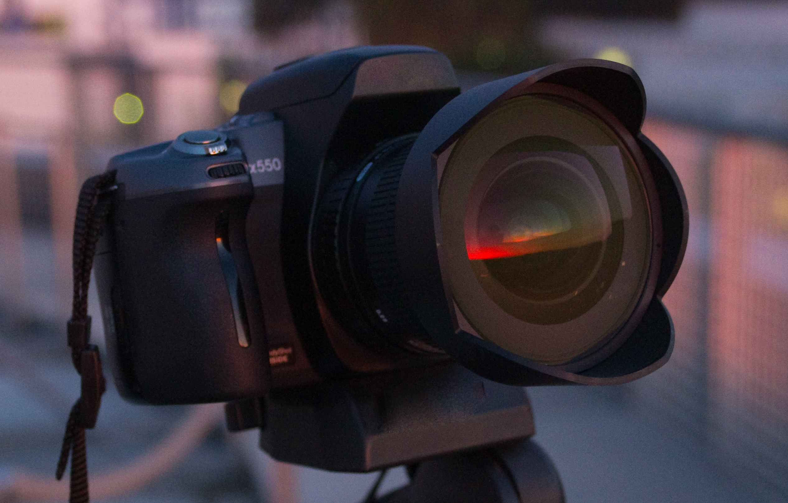 In dem Objektiv der Fotokamera spiegelt sich ein Sonnenuntergang.