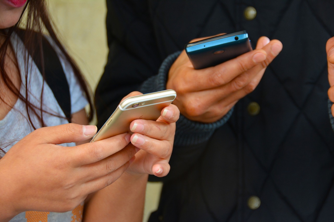 Das Bild zeigt zwei Personen mit Smartphones in den Händen.