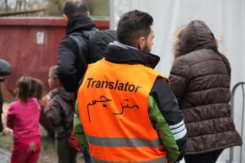 Translator Foto mit Menschen, einer trägt eine Warnweste auf der "Translator" steht