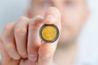 Ein Mann zeigt eine 2-Euro-Münze.