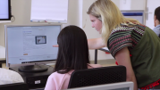 Das Bild zeigt eine Szene aus einem Integrationskurs, zwei Frauen arbeiten am Computer.