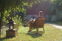 Ein Mann sitzt im Garten und studiert in einem Buch.