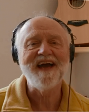 Das Bild zeigt ein Portrait von Hans-Jürgen Boßmeyer, wie er den Mund singend geöffnet hat und Kopfhörer trägt.