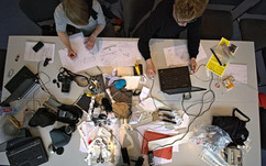 Aktivitäten im Maker Space der SLUB Dresden Blick von oben auf einen Schreibtisch mit vielen Utensilien und zwei Menschen