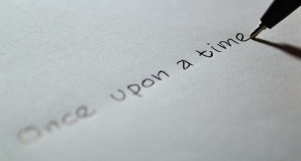 Auf einem weißen Blatt Papier wird mit schwarzer Schrift “once upon a time” (auf deutsch: es war einmal) geschrieben]