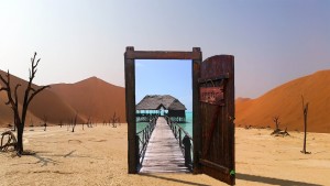 Eine offene Tür in der Wüste, die zum Strand führt.