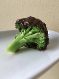 Das Bild zeigt das Foto eines Brokkoliröschens, das mit Schokolade überzogen ist.