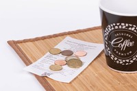 Ein Kaffeebecher mit Kassenbon und Kleingeld