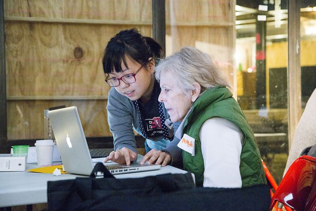 Eine junge Frau zeigt einer Seniorin etwas auf einem Computerbildschirm