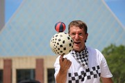 Mann jongliert kleinen und großen Ball auf einer Fingerspitze
